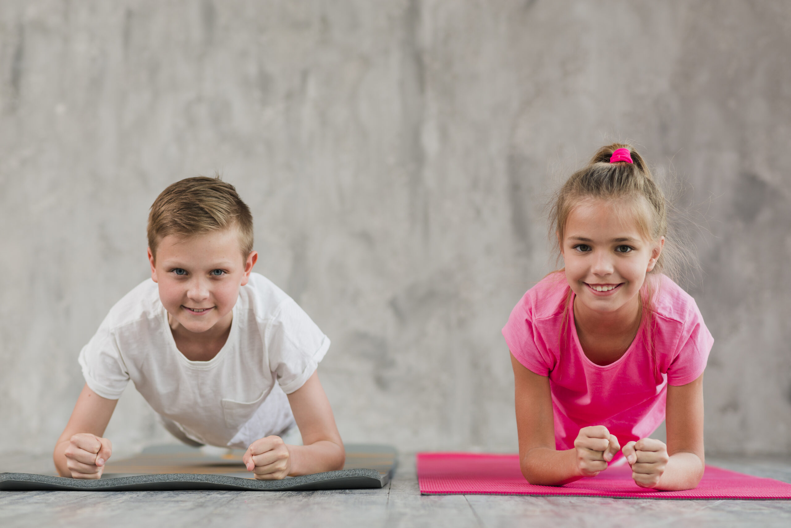 portrait-smiling-boy-girl-doing-fitness-exercise-front-concrete-wall